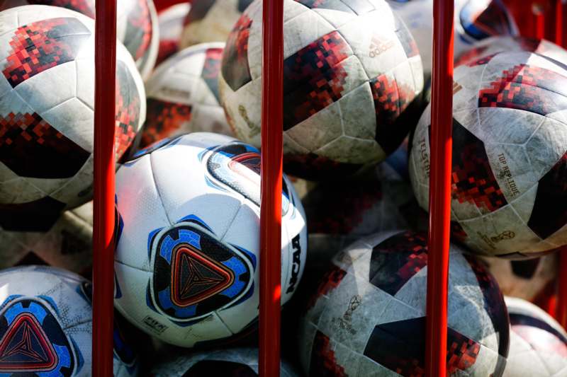 a group of football balls in a red cage