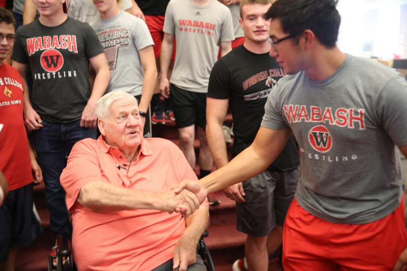 a man shaking hands with a man in a wheelchair