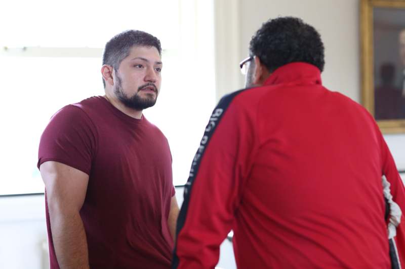 a man in a red shirt talking to another man