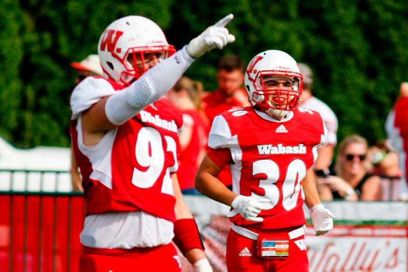 a football players in red and white uniforms pointing at each other