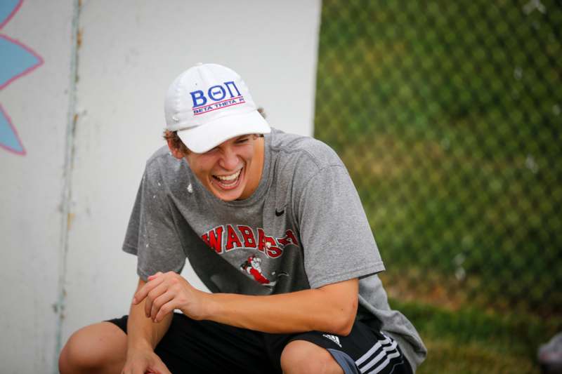 a man laughing while wearing a hat