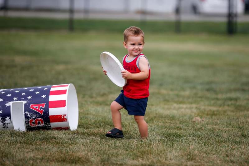 a child holding a frisbee next to a barrel