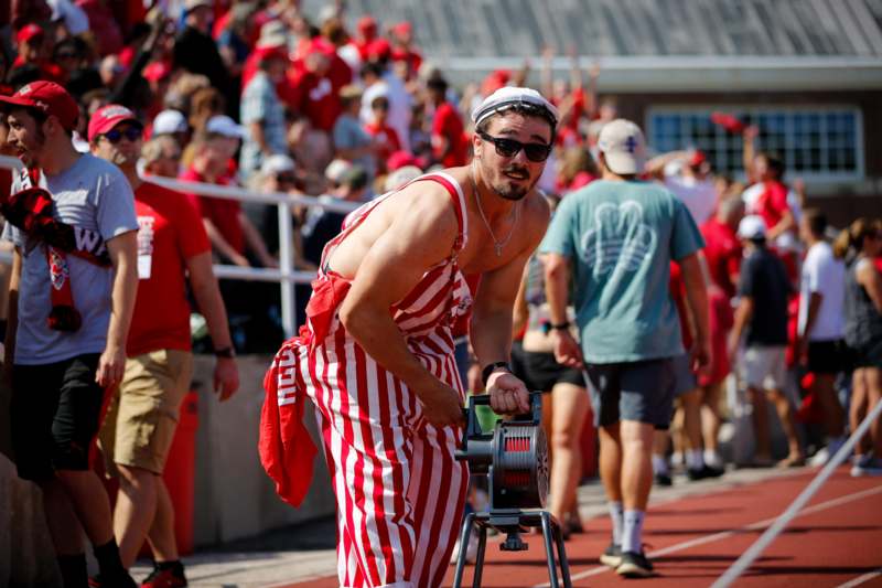 a man in a striped overalls and sunglasses on a track with a crowd