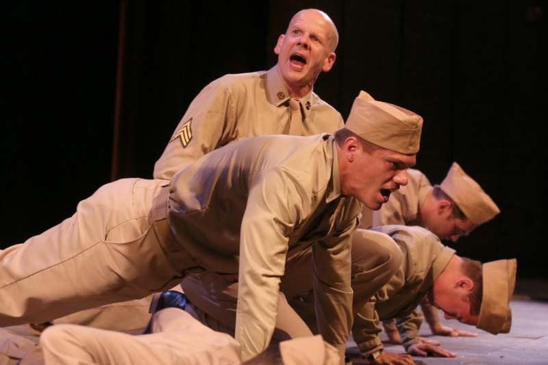 a group of men in tan uniforms on a stage