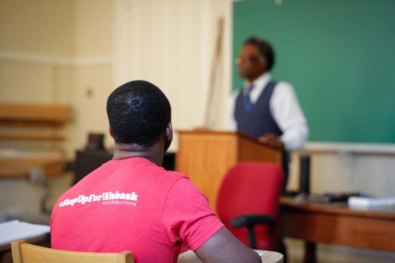 a man in a red shirt in front of a man in a classroom