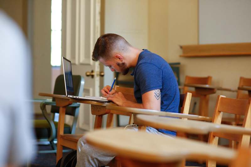 a man sitting at a desk writing on a laptop