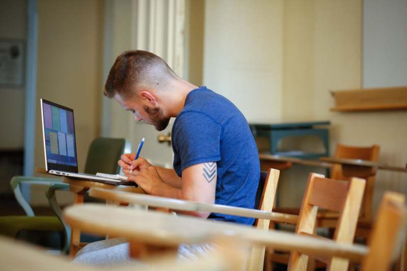 a man sitting at a desk with a laptop and pen