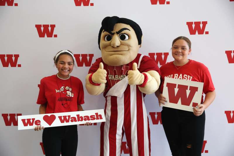 two girls standing next to a mascot