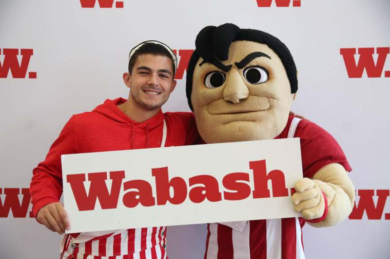 a man holding a sign with a mascot