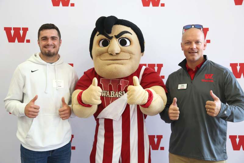 two men posing with a mascot
