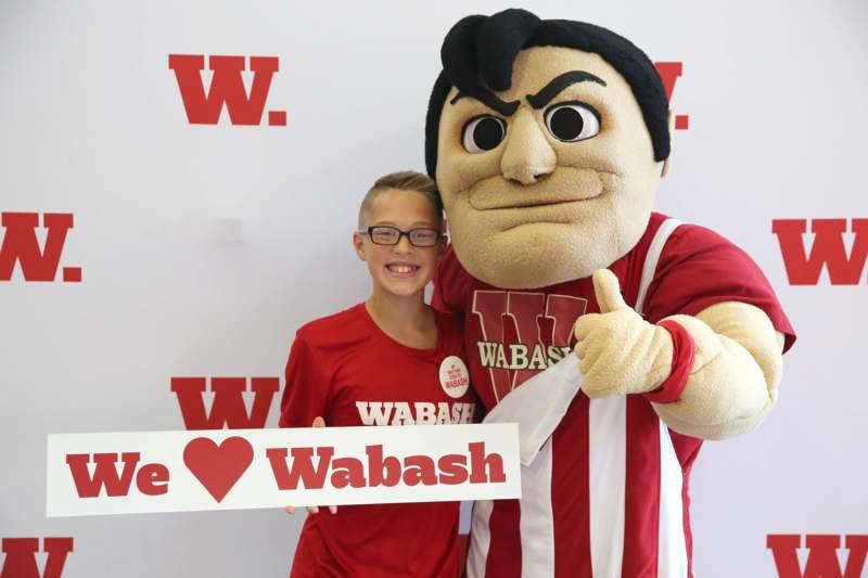 a boy holding a sign next to a person in a mascot garment