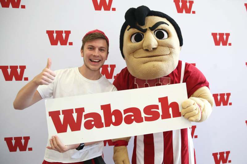 a man holding a sign next to a person in a mascot garment