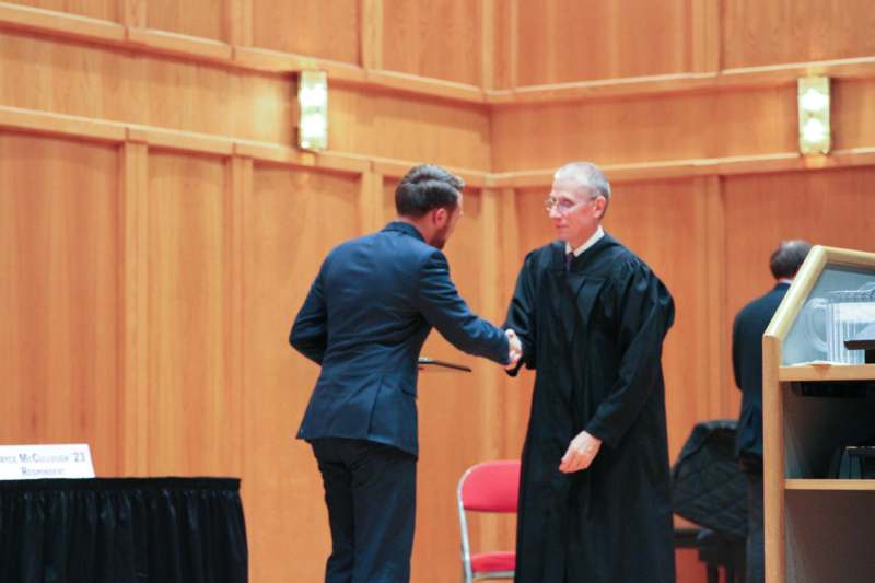 a man shaking hands with another man in a robe