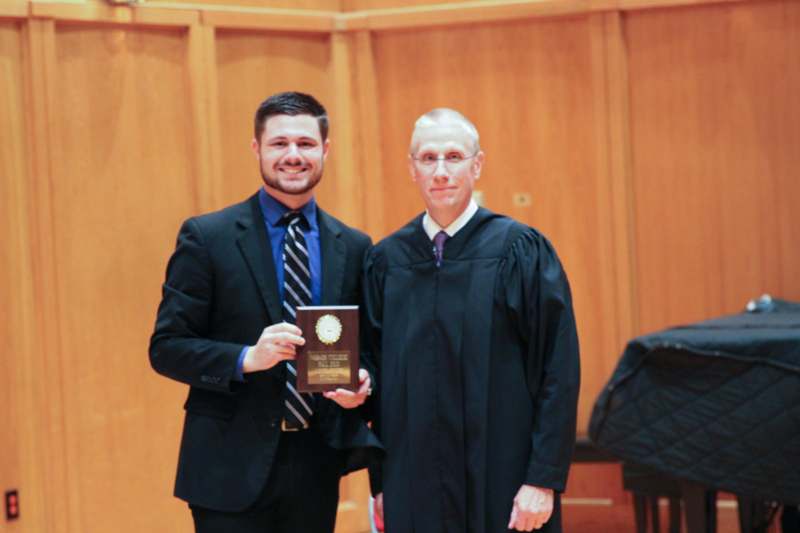 a man in a black robe holding a plaque with a man in a black robe