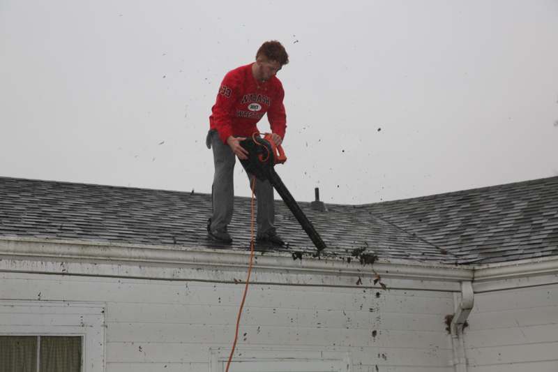 a man using a blower to clean the roof of a house