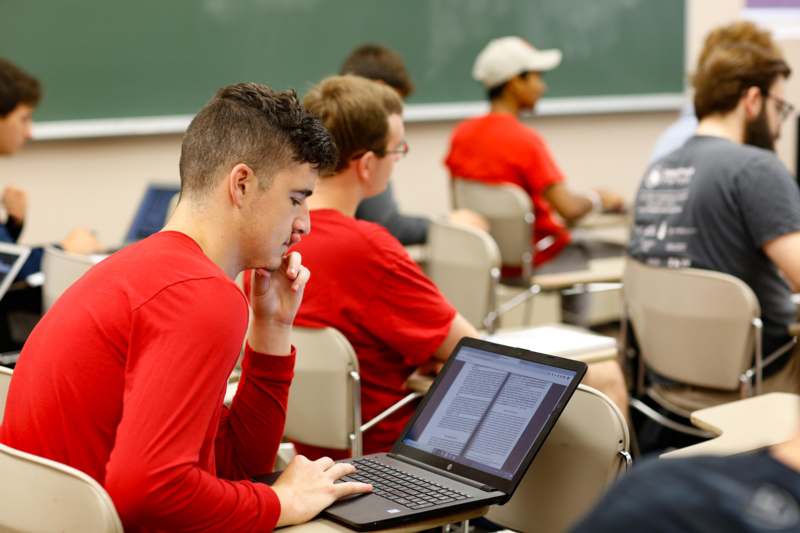 a man in a red shirt using a laptop
