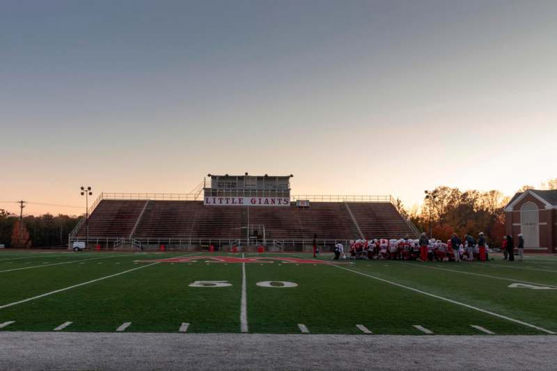 a football field with a group of people standing in front of the stands