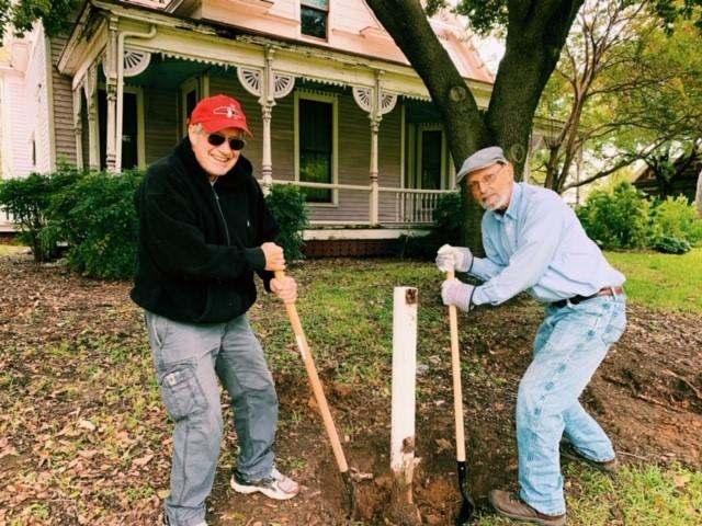 a couple of men digging a hole in the ground