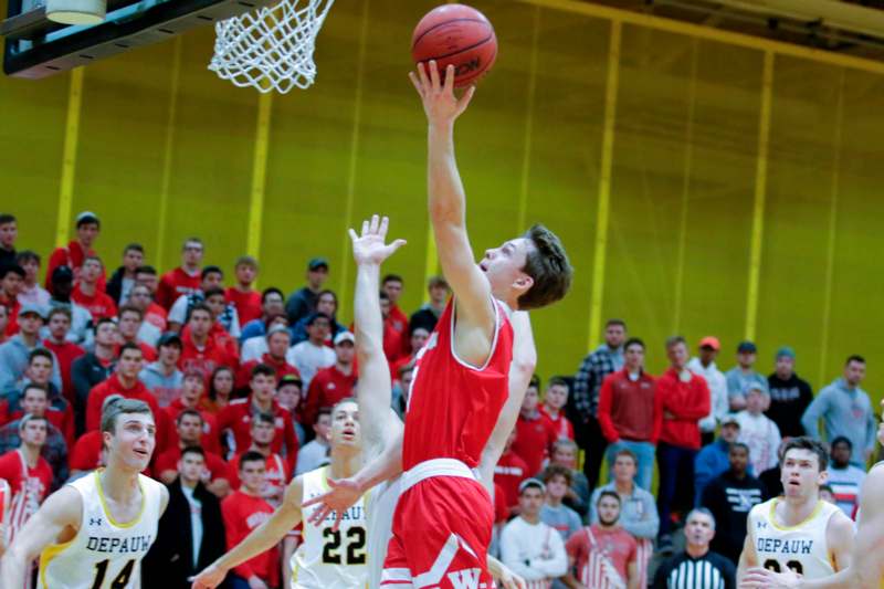 a basketball player in red and white playing in a gym