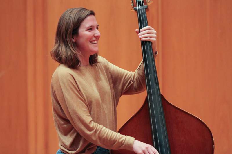 a woman smiling while holding a bass