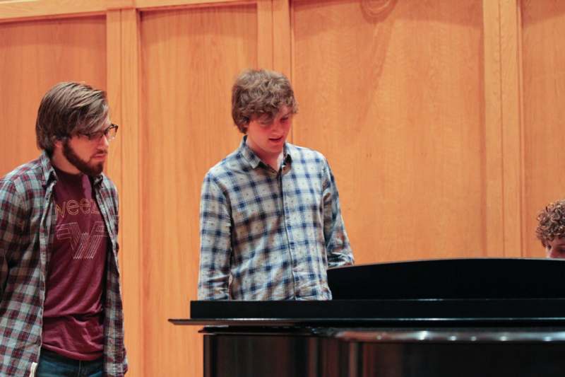 a man standing next to a man standing next to a piano