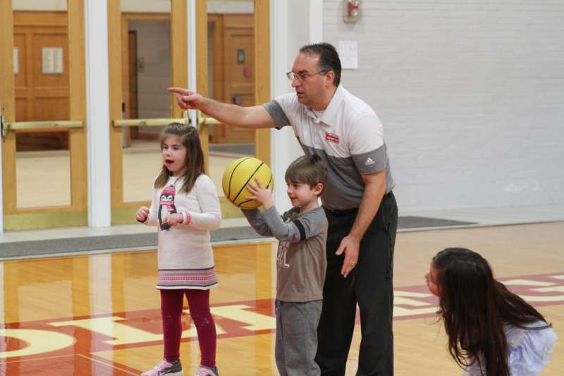 a man pointing at a basketball with kids