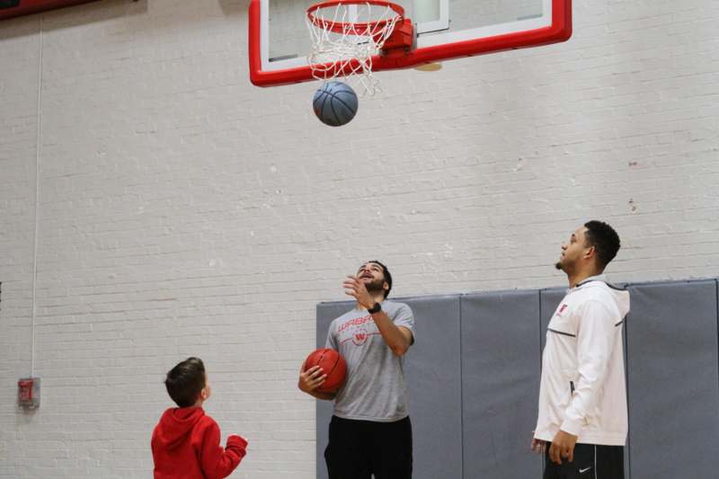 a man playing basketball with a boy and a basketball in a gym