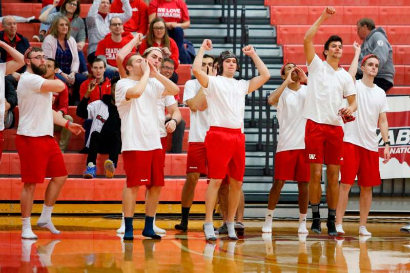 a group of men in red shorts and white shirts with their hands up