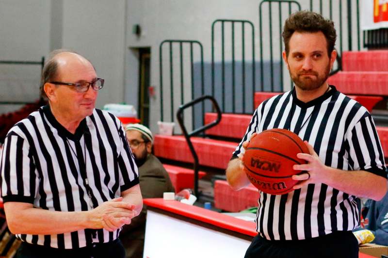 two men in black and white striped shirts holding basketballs