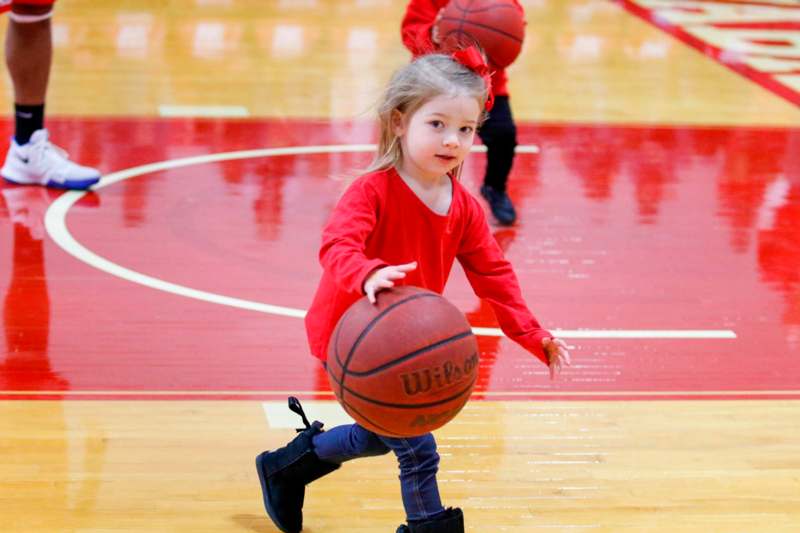 a girl in a red shirt holding a basketball