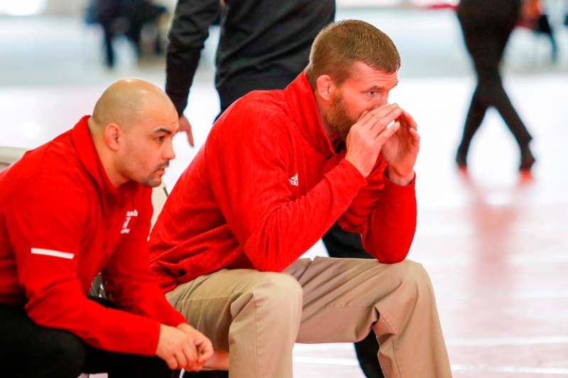 a man in red shirt sitting on a floor with another man in red shirt