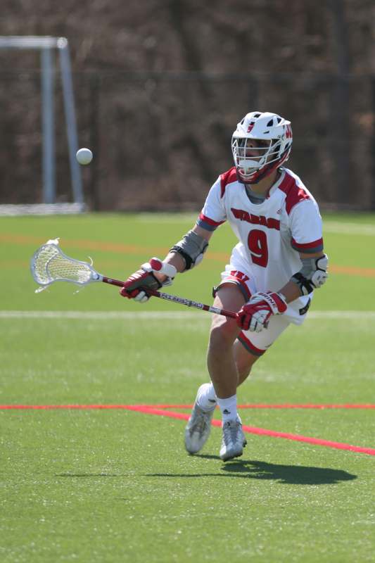 a man in a white and red uniform with a lacrosse stick