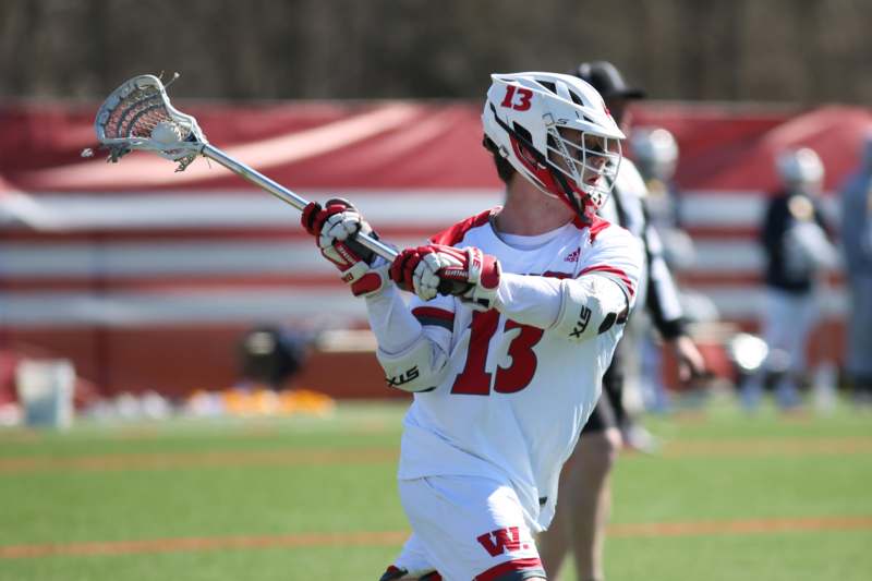 a man in a white and red uniform holding a lacrosse stick
