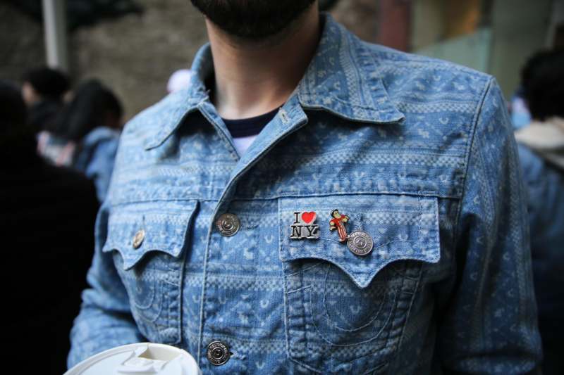 a person wearing a denim jacket with pins on it
