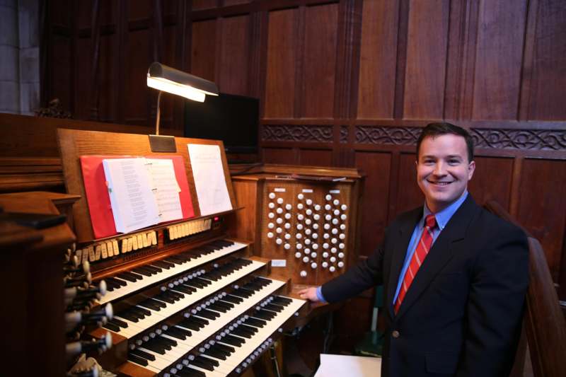 a man standing next to a pipe organ