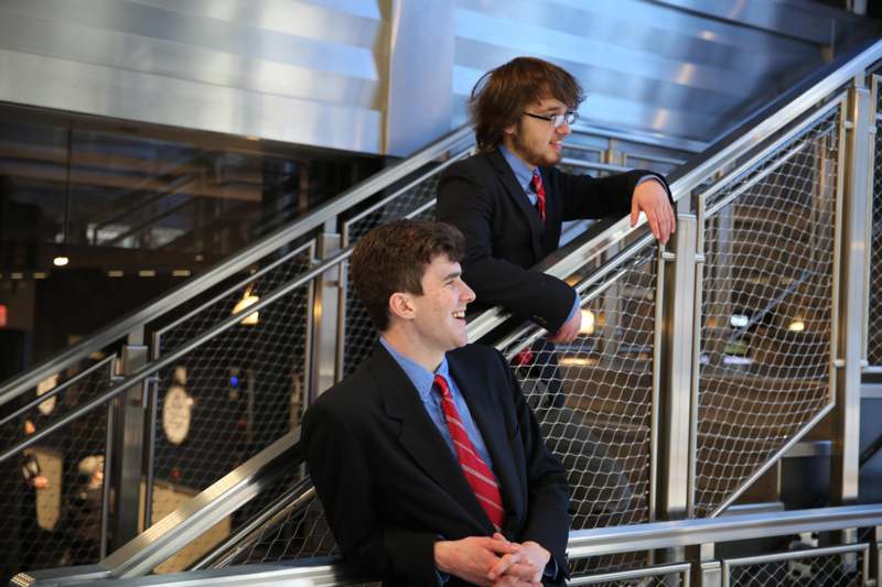 two men in suits and ties sitting on a staircase