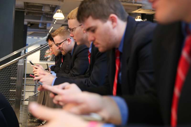 a group of men in suits looking at their phones