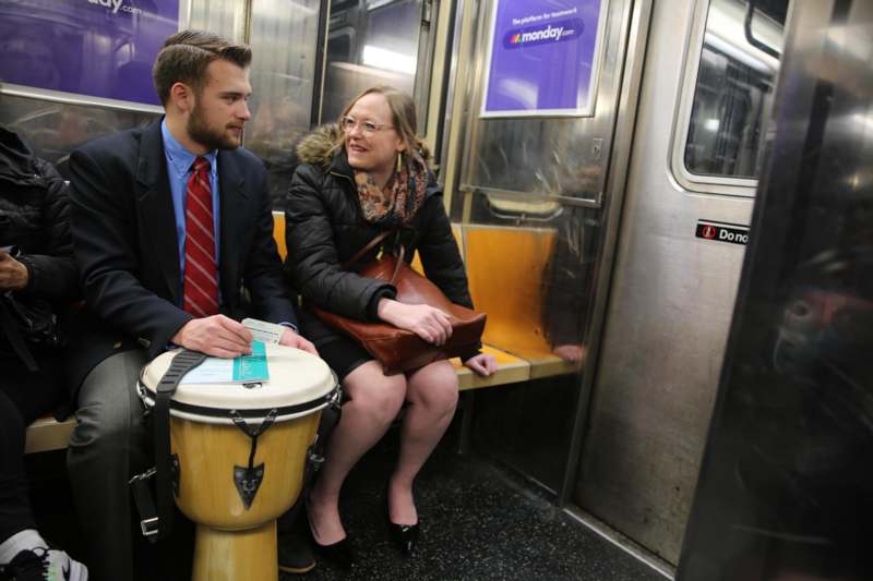 a man and woman sitting on a bench in a subway