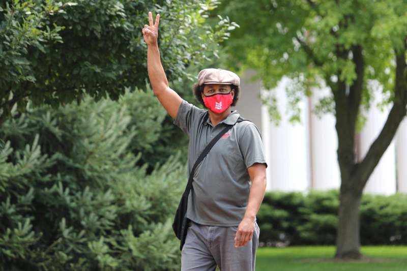 a man wearing a red face mask and holding up his hand
