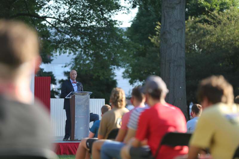 a man standing at a podium with a crowd of people watching