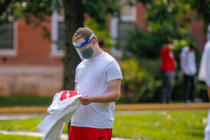 a man wearing a face mask and holding a white shirt