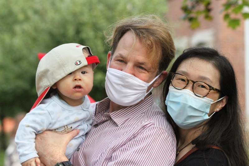 a man holding a baby wearing a face mask