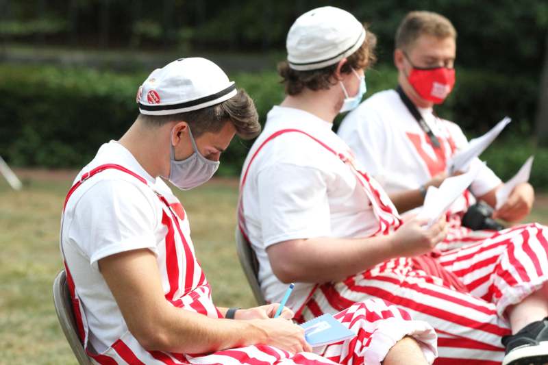 a group of men wearing masks and sitting in a row