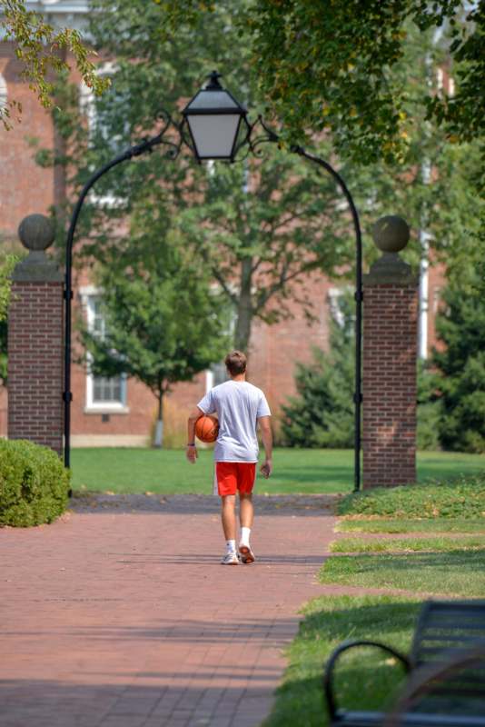 a man walking on a brick path with a basketball
