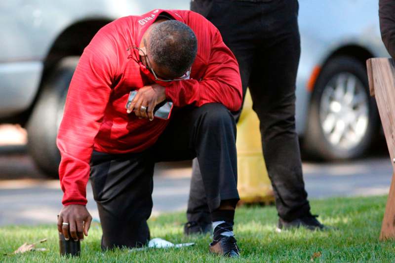 a man in a red shirt kneeling on grass