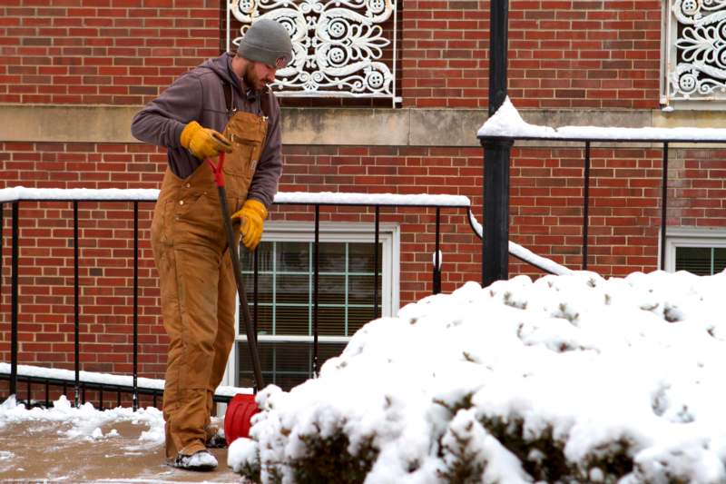 a man in overalls shoveling snow