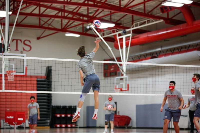 a man jumping in the air to hit a volleyball net