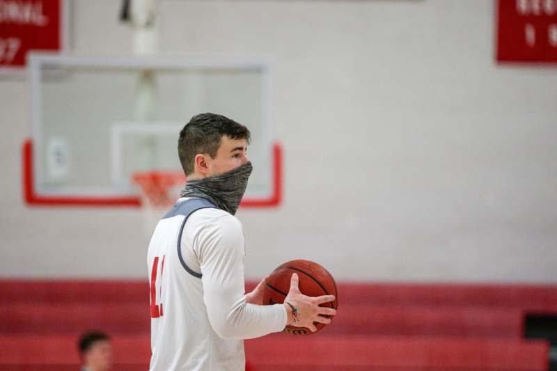 a man wearing a scarf over his face holding a basketball