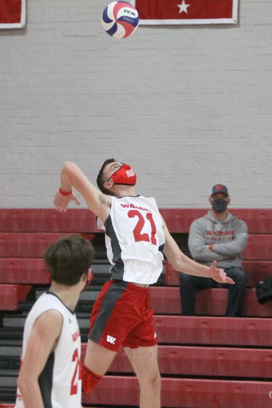 a man in a white jersey and red shorts with a face mask