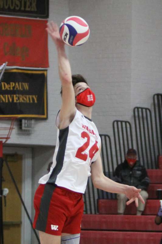 a man in a white jersey and red shorts jumping to dunk a ball